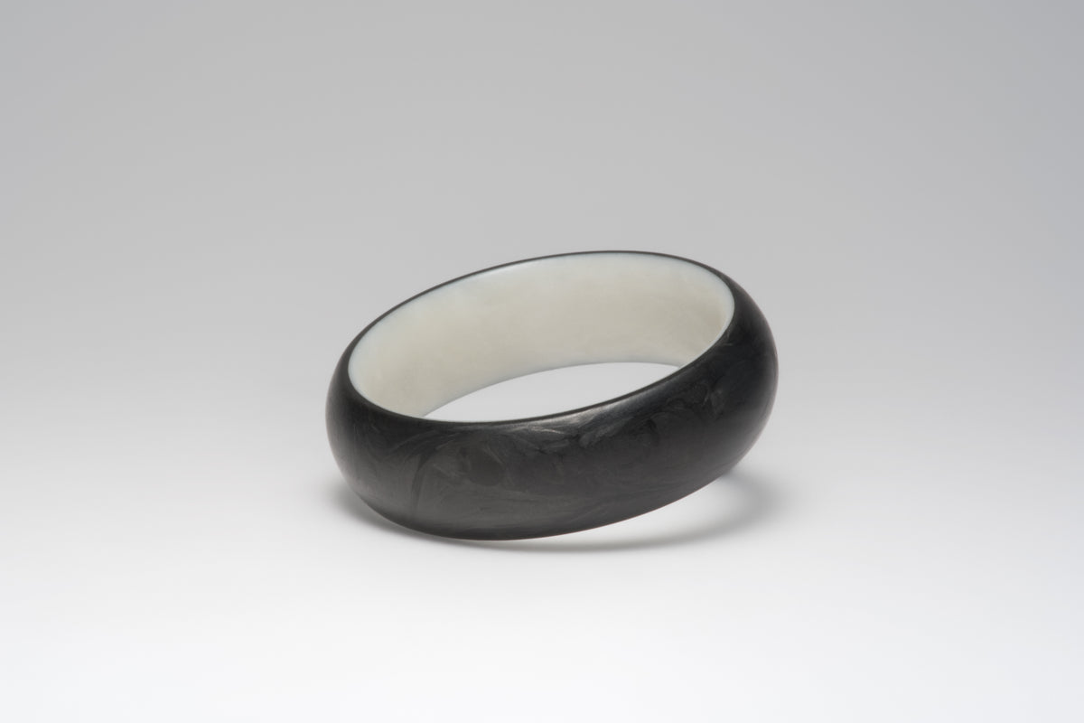 Bamboo silk and forged carbon fiber mens wedding band lying on its side